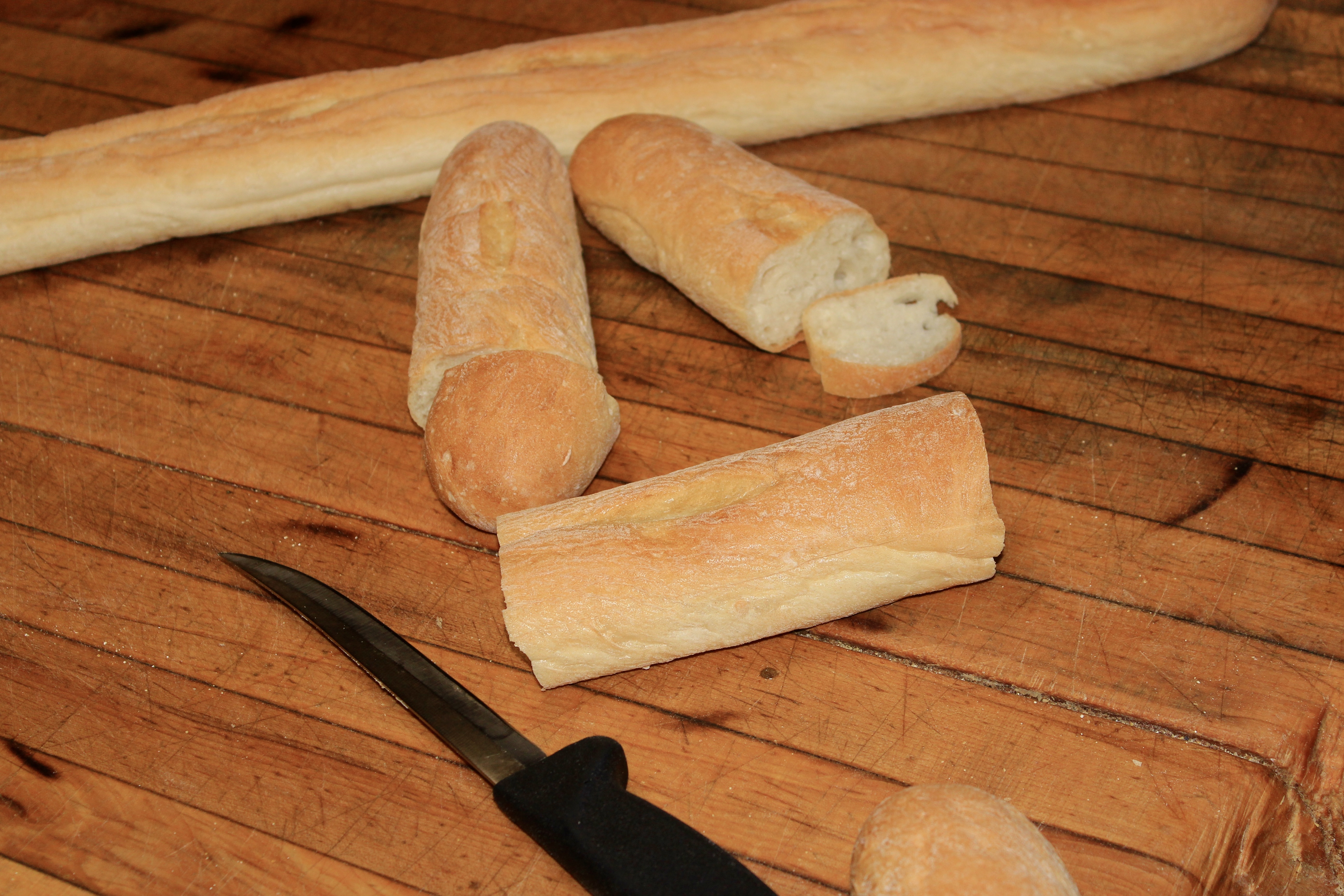 Fresh French bread sliced to order on a wood cutting board