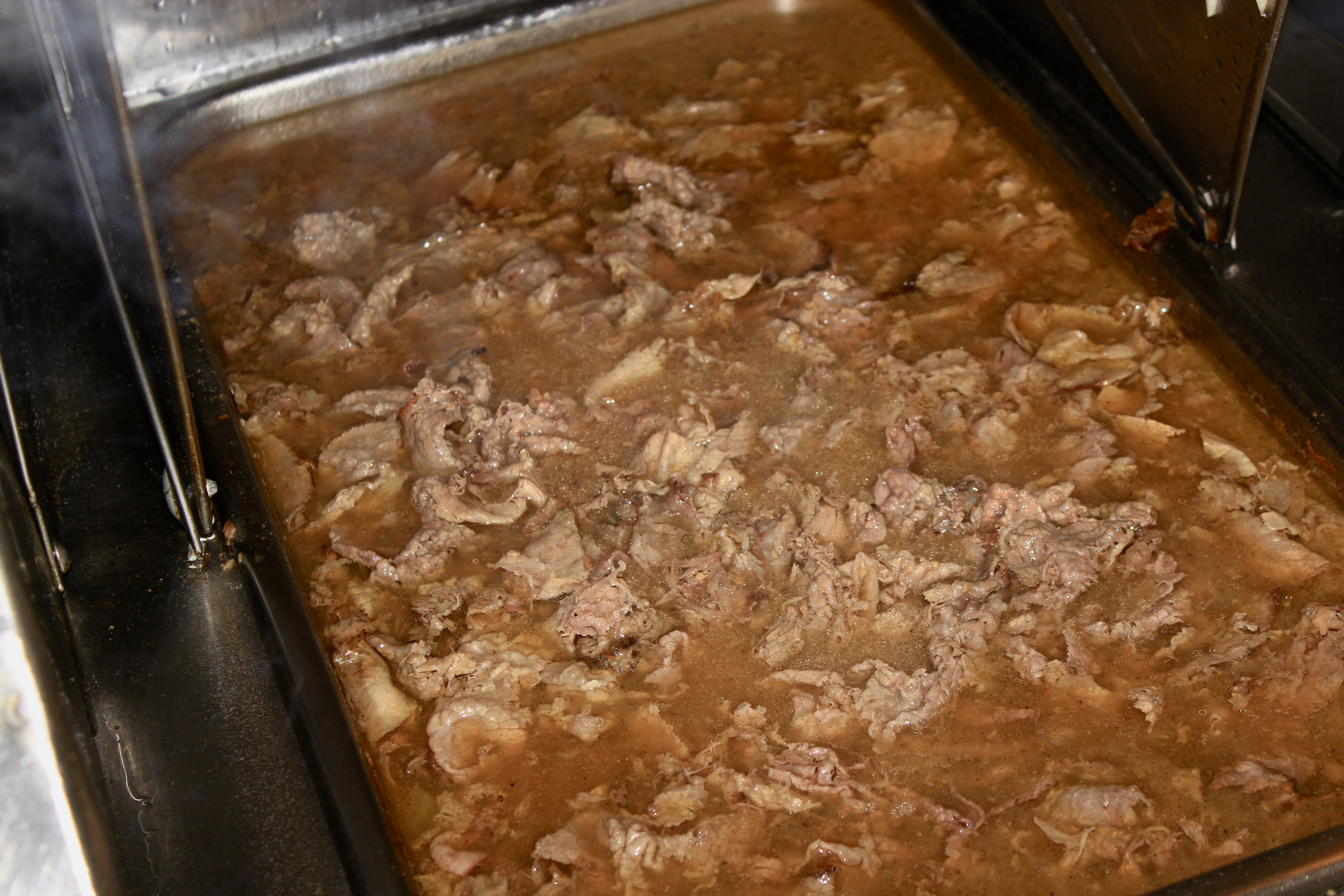 Homemade Italian beef simmering in seasoned gravy