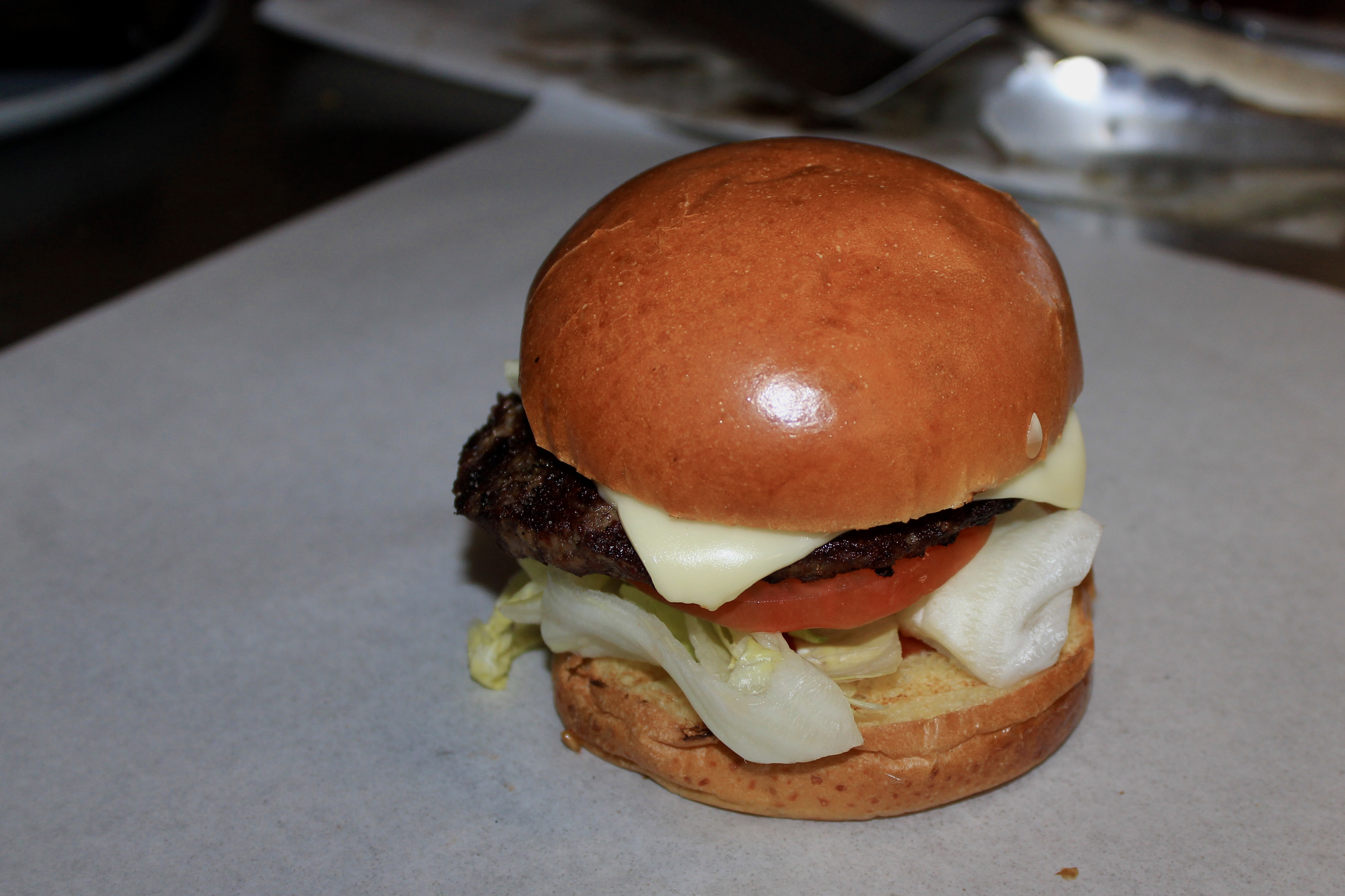 Char-grilled 1/3 lb cheeseburger with American Swiss cheese, lettuce, tomato, and onion on a toasted brioche bun