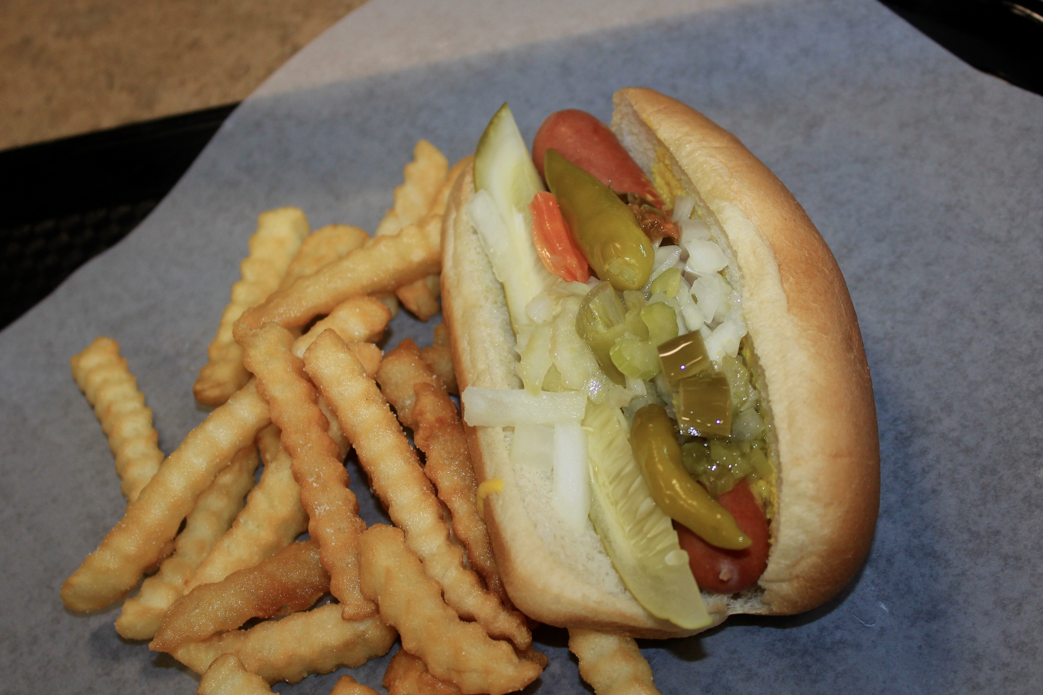 Vienna Beef Chicago-style hot dog with mustard, relish, onion, tomato, sport peppers and pickle spear, served with crinkle-cut fries